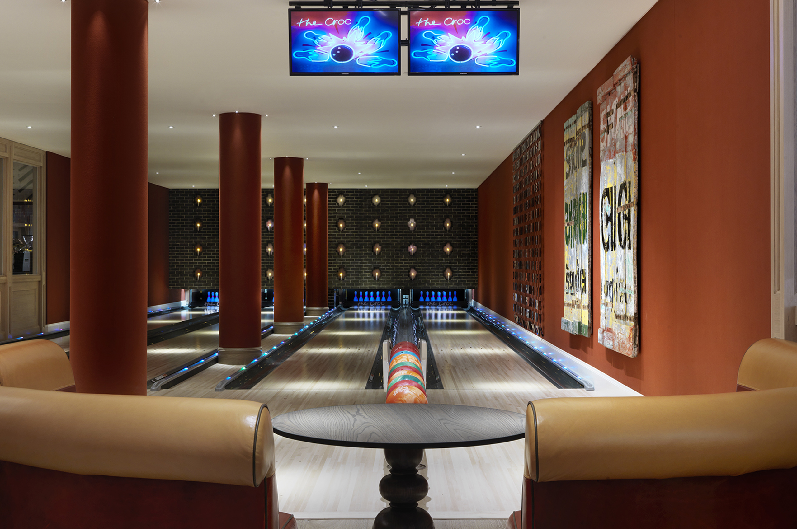 The Croc bowling alley at Ham Yard Hotel — four lanes stretching into the distance, neon signage overhead, terracotta columns and a colourful bowling ball in the foreground